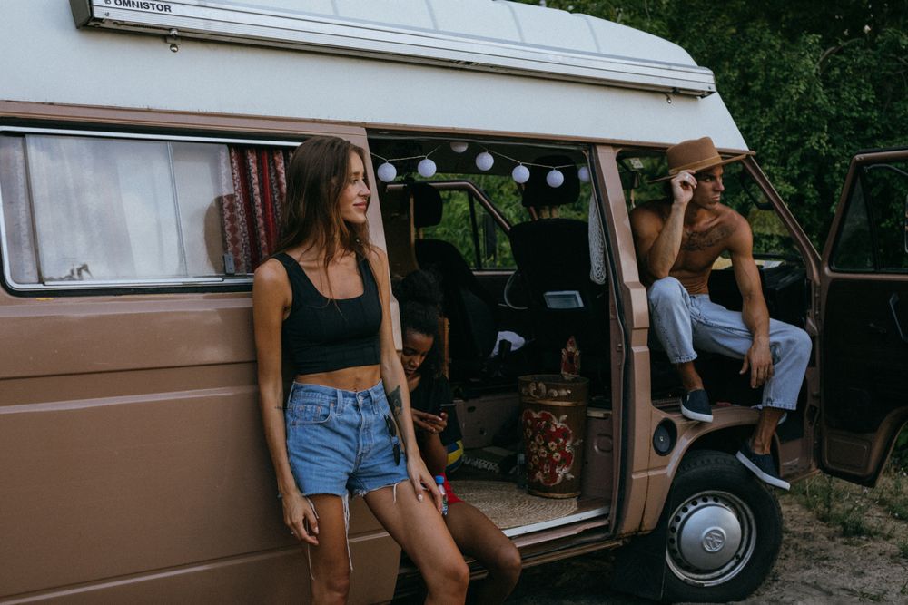 Three friends hanging out around their camper van at golden hour